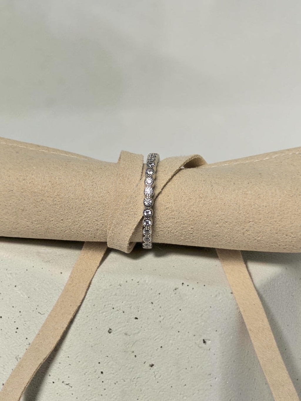 reveriebygemma adjustable sterling silver half-eternity ring with pavé cubic zirconia stones on a beige velvet roll