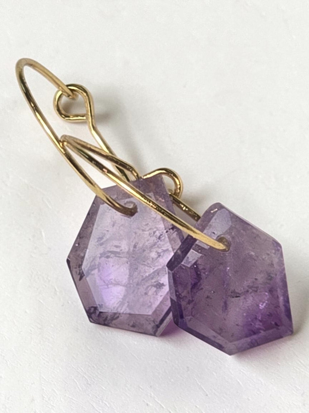 reveriebygemma Lucid Drops amethyst huggie earrings featuring faceted purple gemstones on 14kt gold plated hoops.