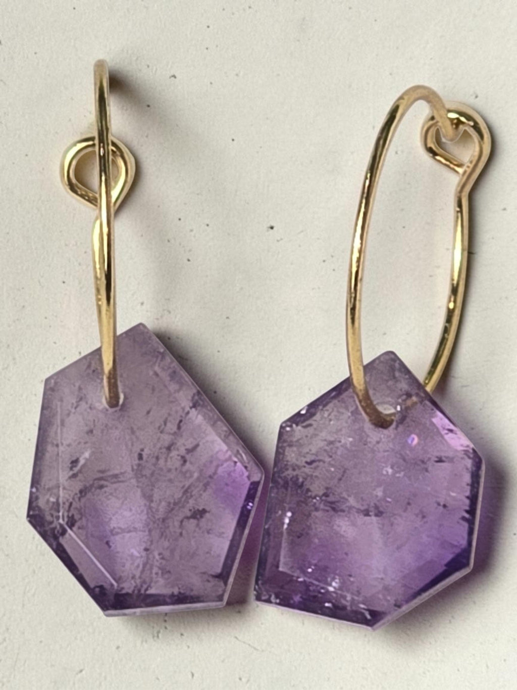 reveriebygemma Lucid Drops amethyst huggie earrings featuring faceted purple gemstones on 14kt gold plated hoops.