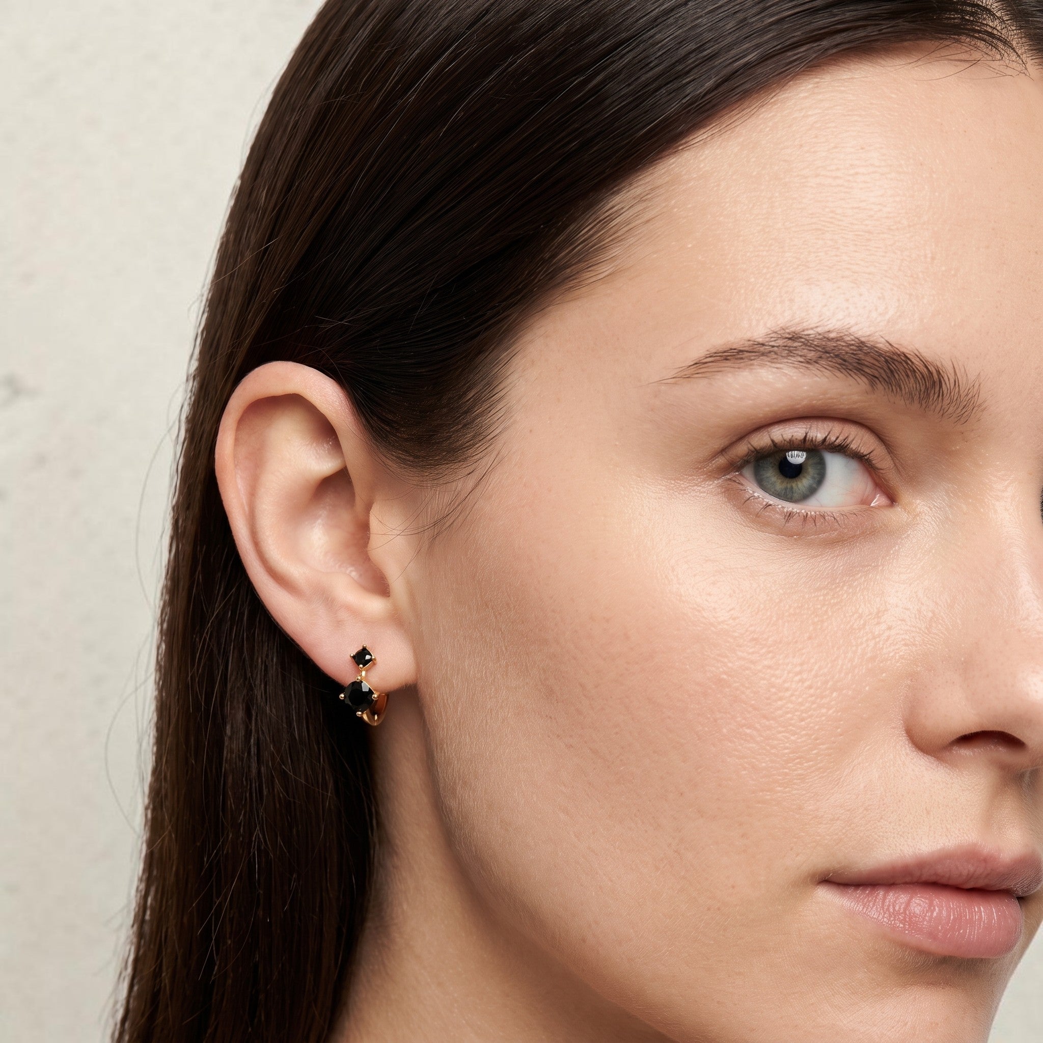 reveriebygemma black onyx double stone mini huggie hoops in sterling silver worn on a model's earlobe