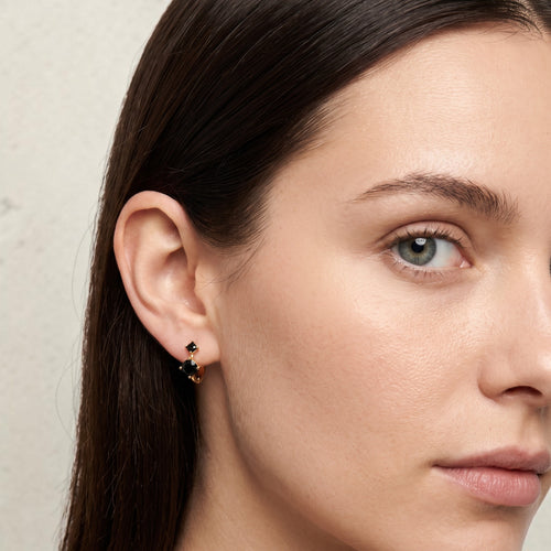 reveriebygemma black onyx double stone mini huggie hoops in sterling silver worn on a model's earlobe