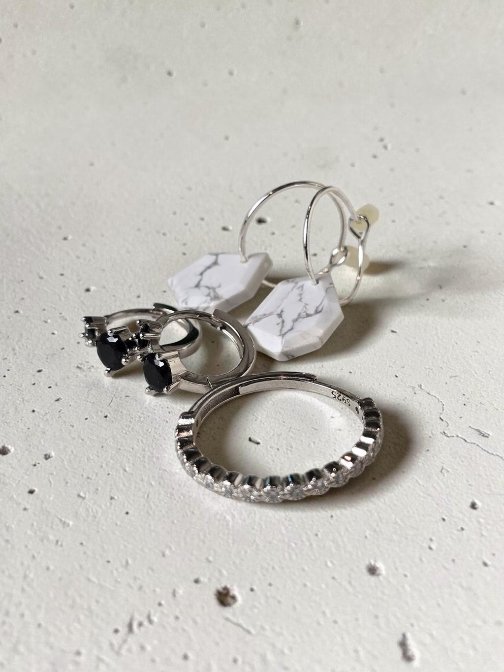 reveriebygemma black onyx double stone sterling silver huggie hoops displayed with white marble earrings and a ring