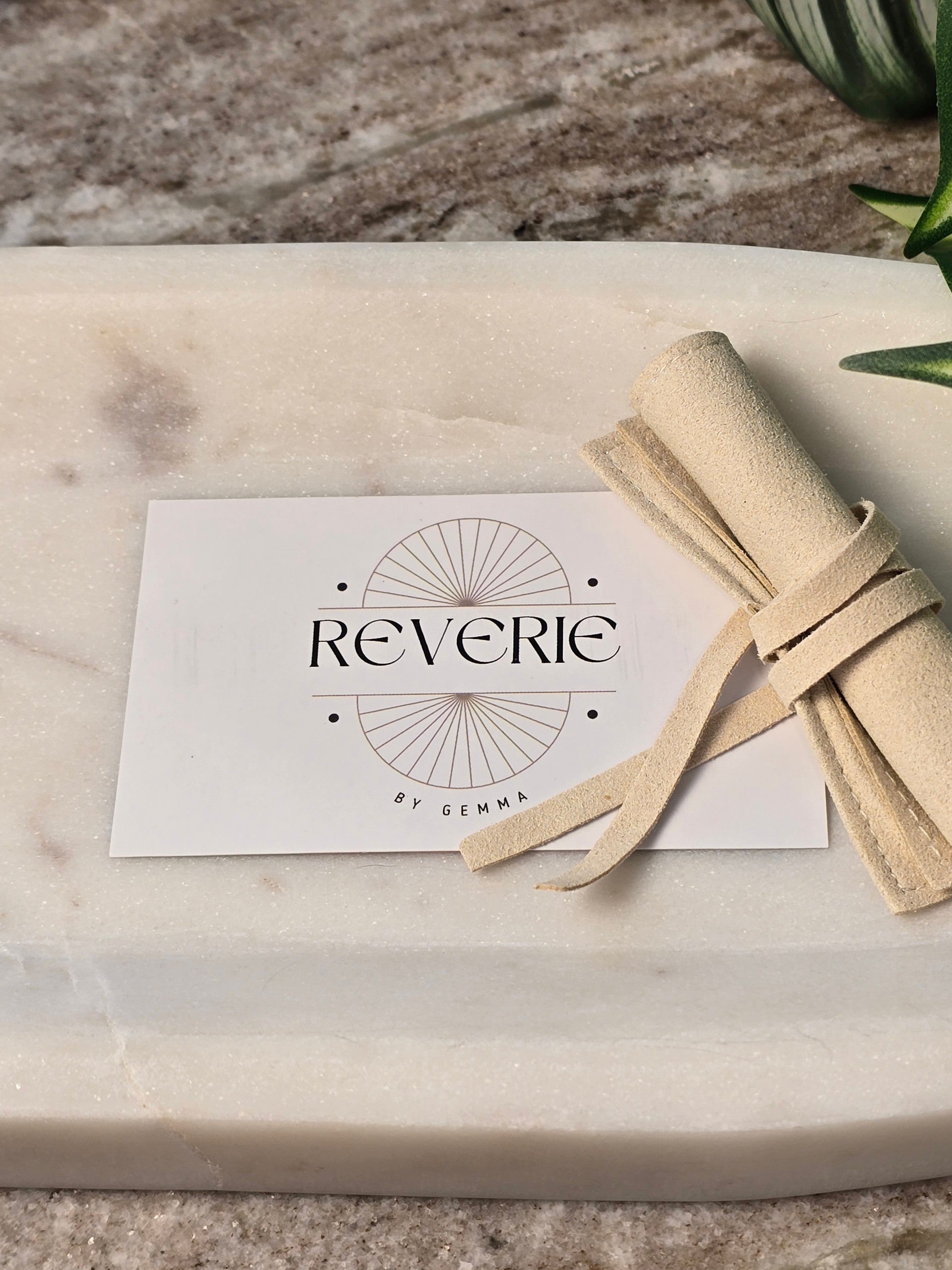 reveriebygemma branded card and soft beige luxury velvet pouch on a white marble surface