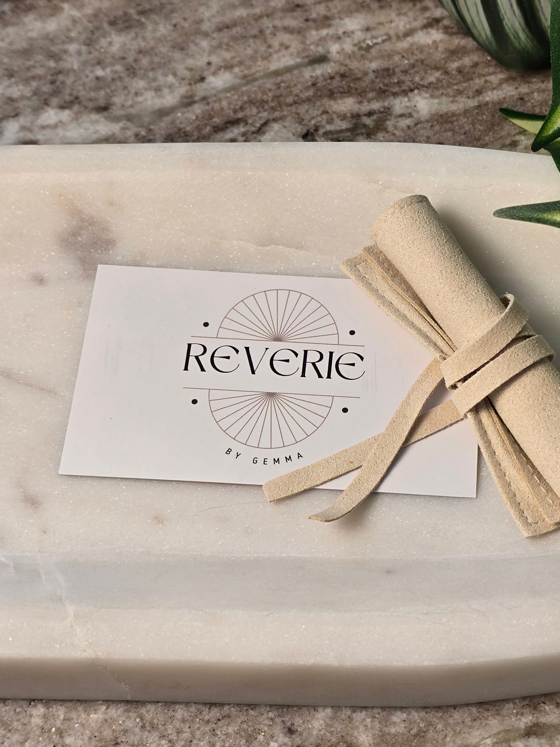 reveriebygemma branded card and luxury velvet pouch on a marble surface for jewelry packaging