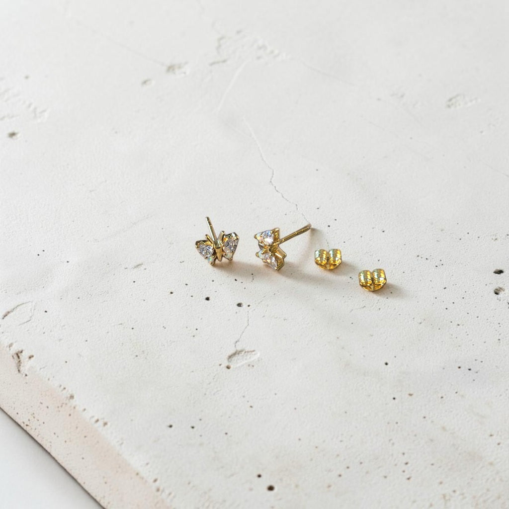 reveriebygemma butterfly stud earrings in 18kt gold vermeil with simulated diamonds and opals on a concrete display