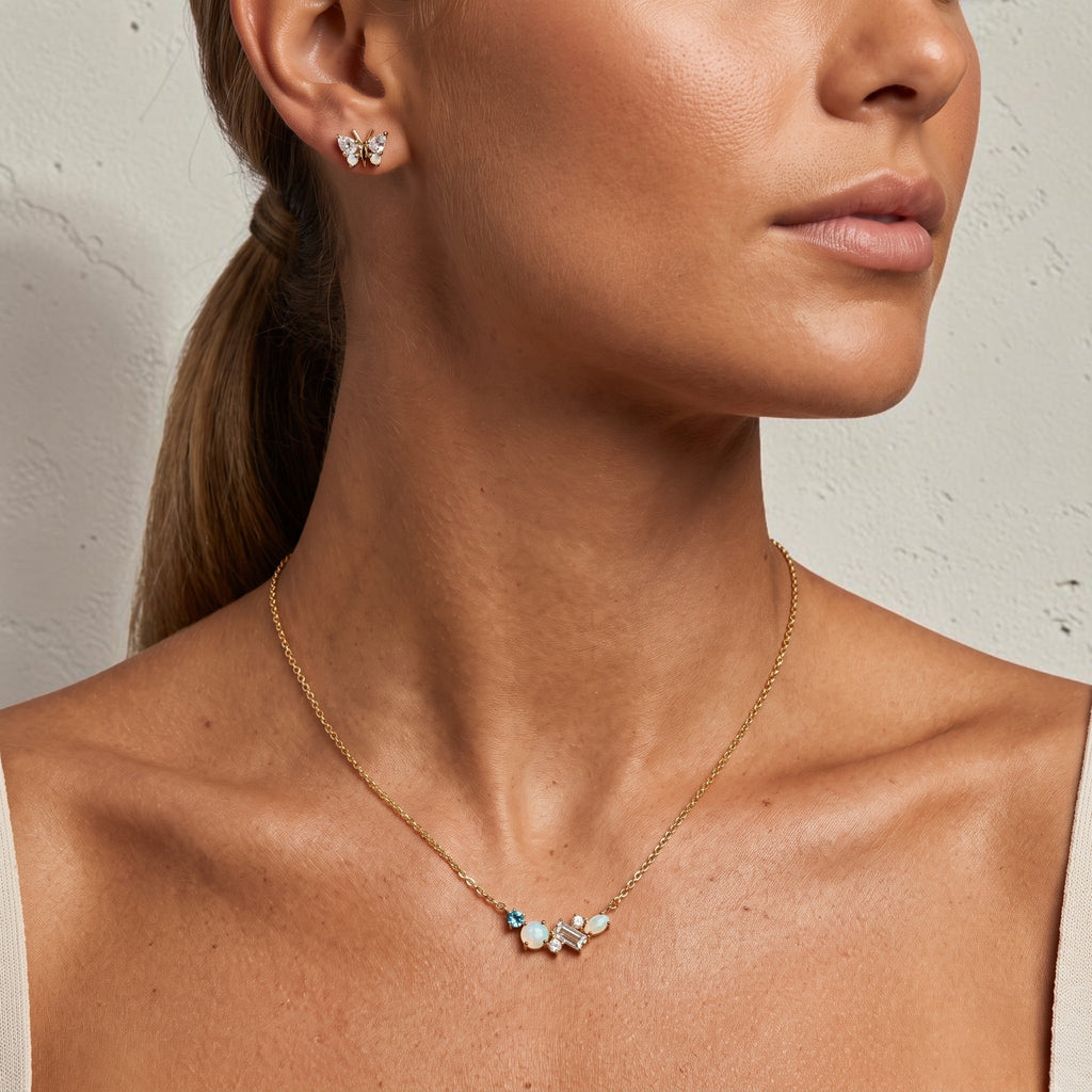 reveriebygemma butterfly stud earrings in 18kt gold vermeil with simulated opal and diamond on a model