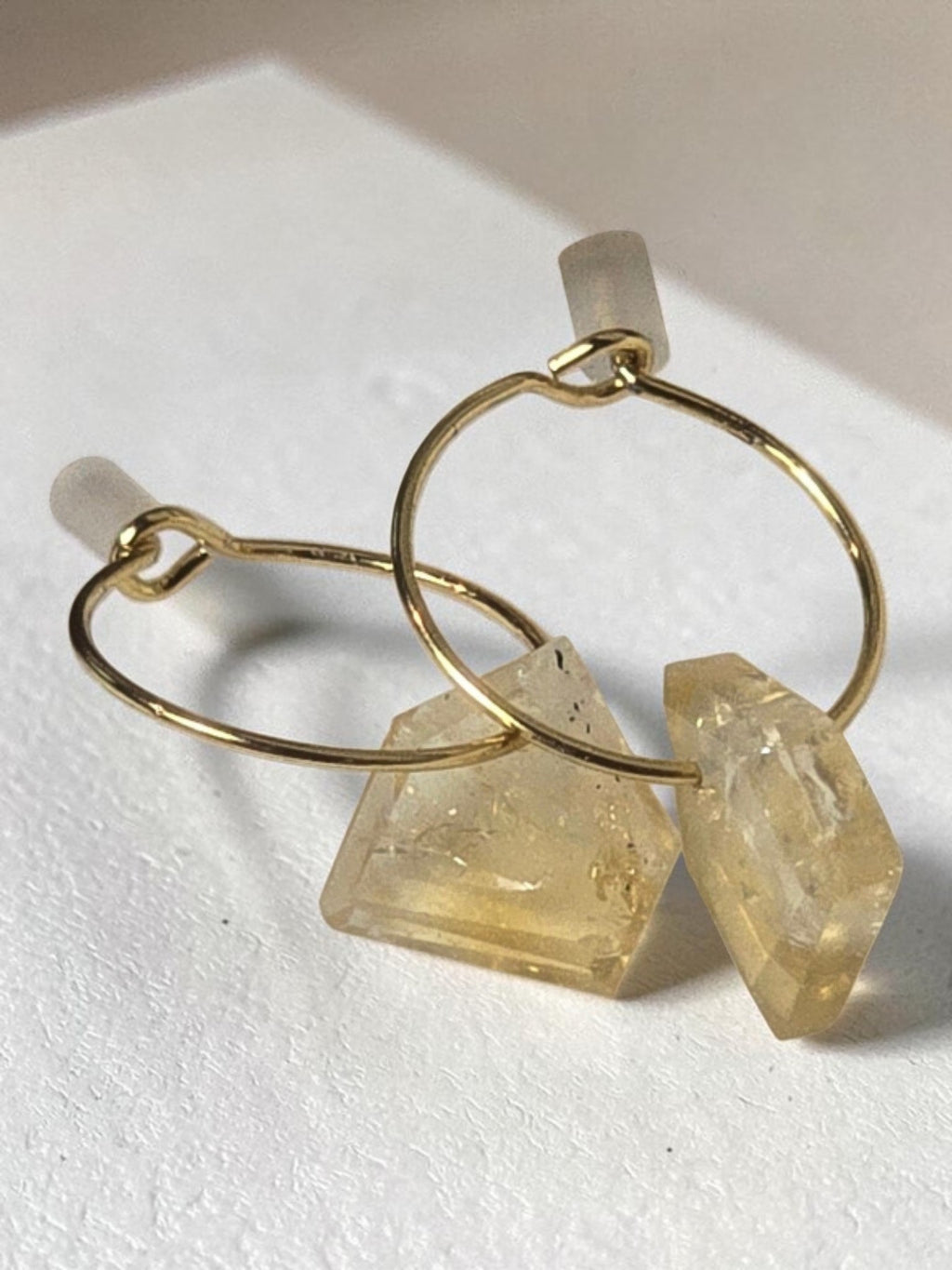 reveriebygemma gold-plated mini hoop earrings featuring raw-cut geometric citrine gemstone droplets on a marble surface