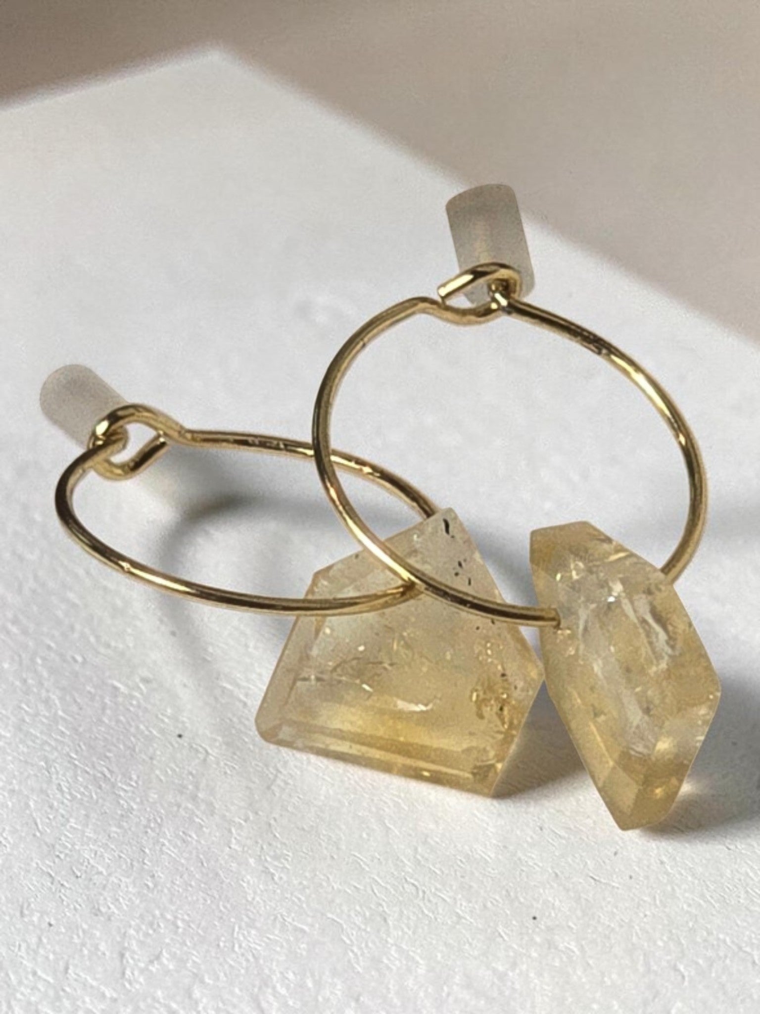 reveriebygemma gold-plated mini hoop earrings featuring raw-cut geometric citrine gemstone droplets on a marble surface