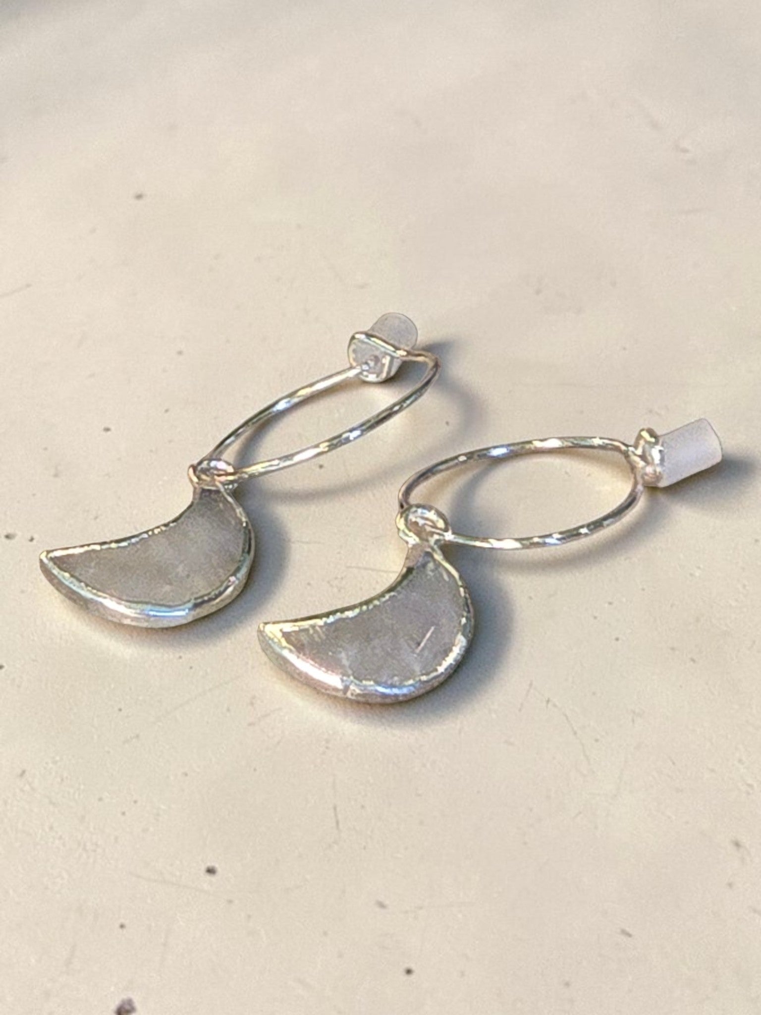 reveriebygemma Selene crescent moonstone mini huggie hoops in 925 sterling silver with a whimsical celestial design.