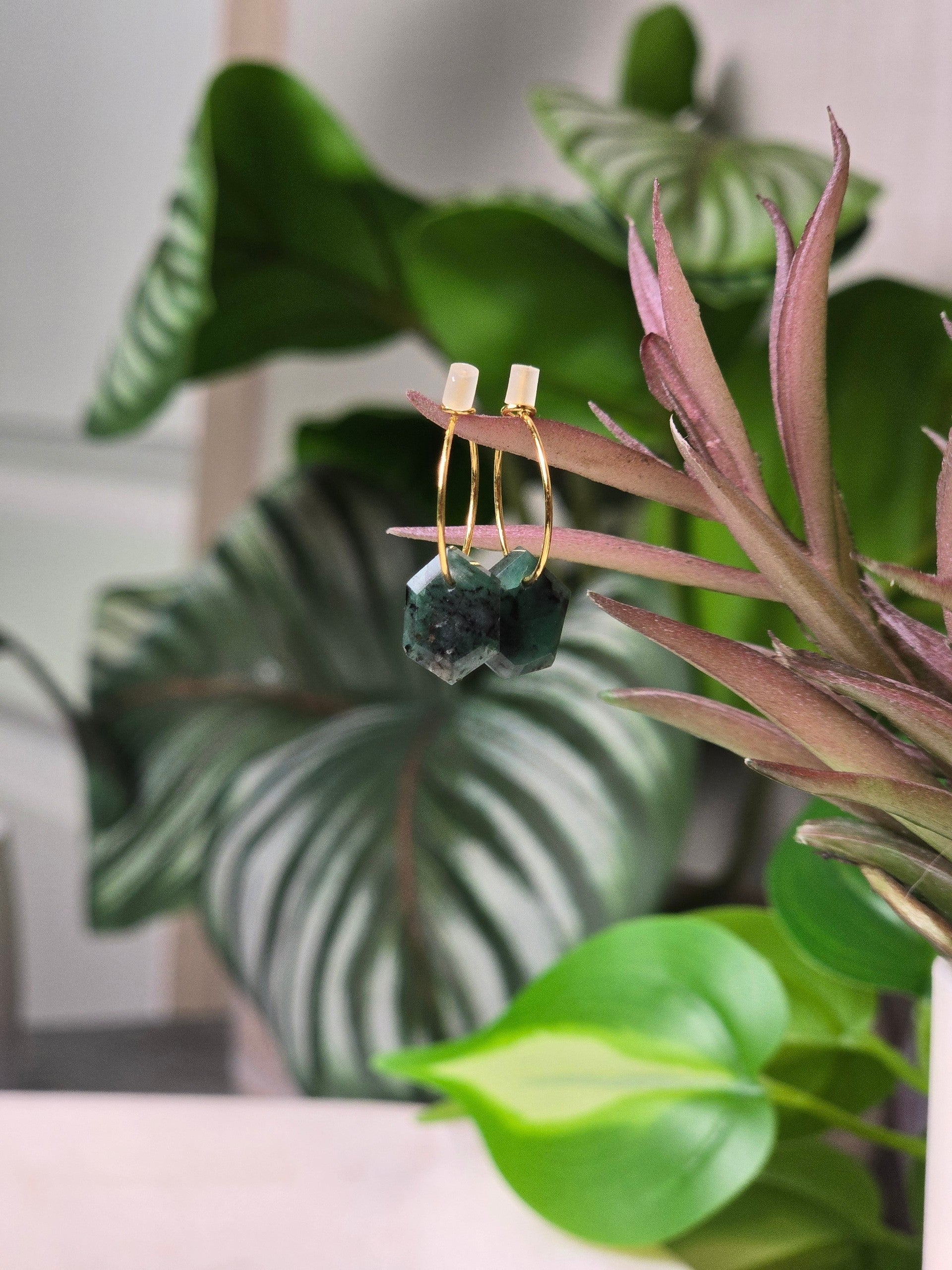 reveriebygemma geometric emerald huggie earrings with raw green crystals on 14kt gold plated hoops against lush foliage