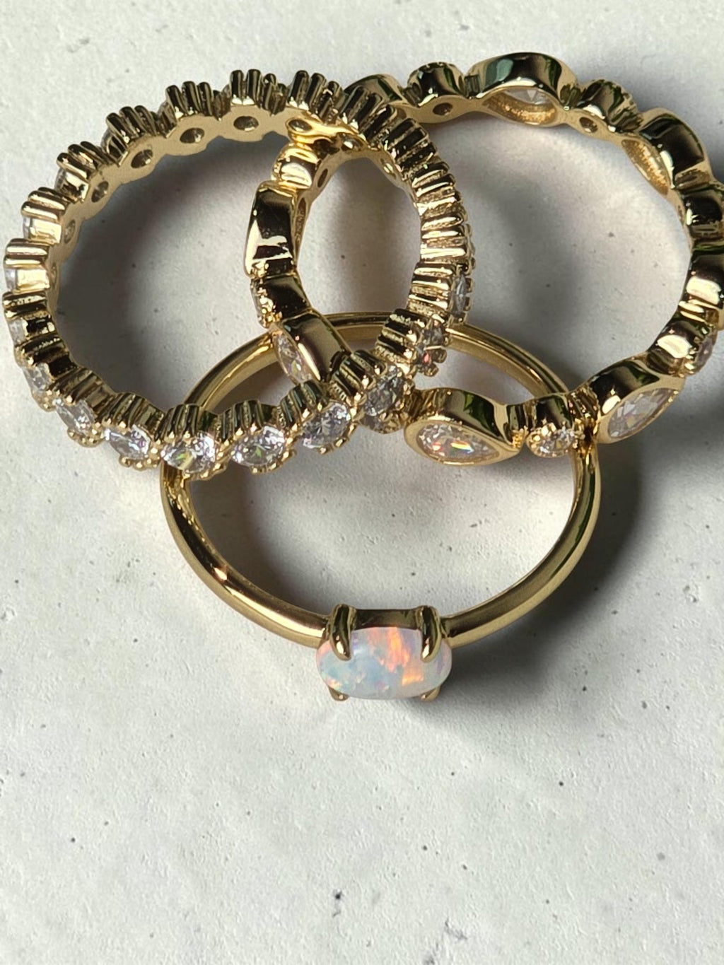 reveriebygemma fire opal stacking ring in 14kt gold plated silver, shown with pear and eternity bands on marble