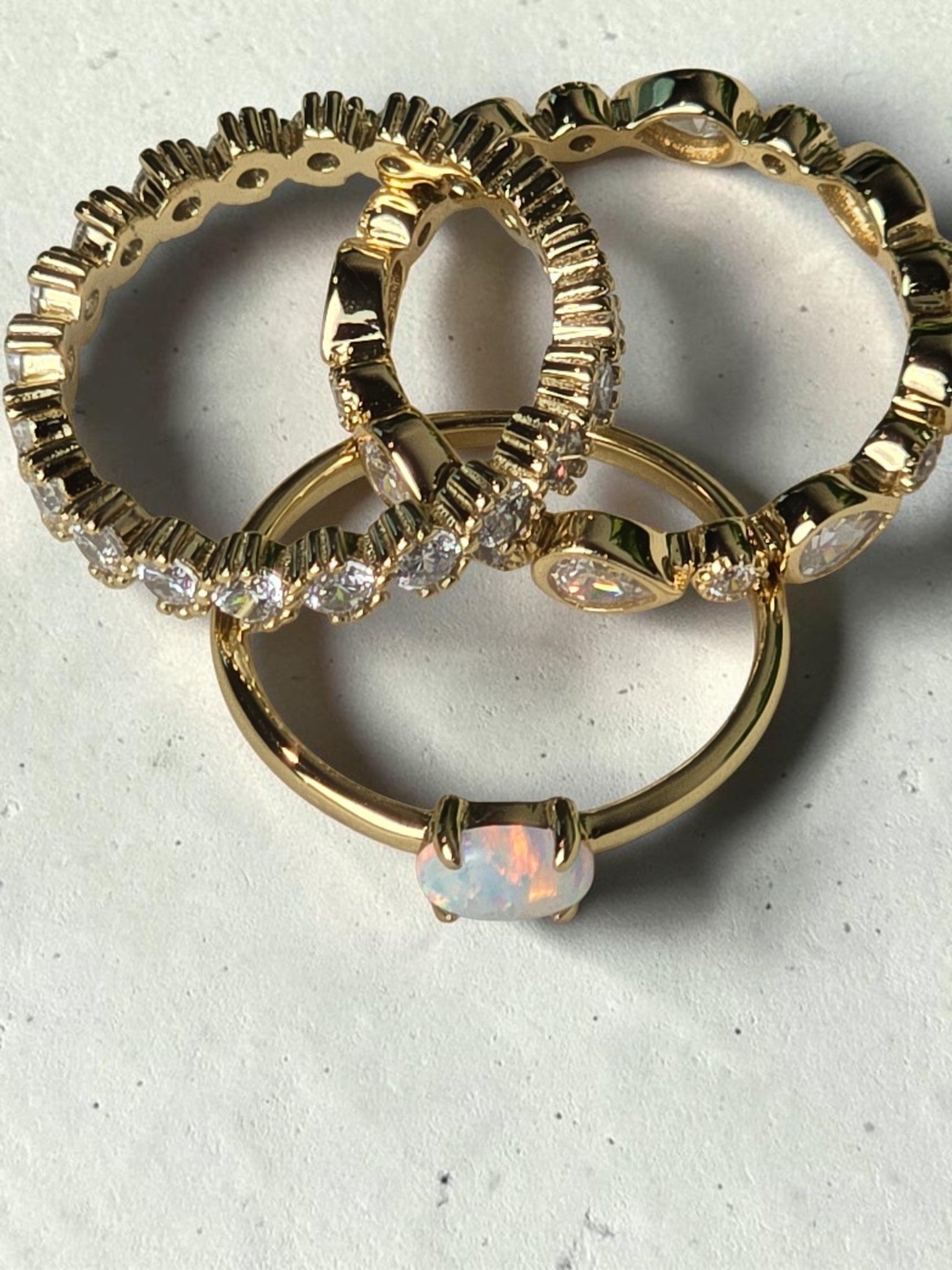 reveriebygemma fire opal stacking ring in 14kt gold plated silver, shown with pear and eternity bands on marble