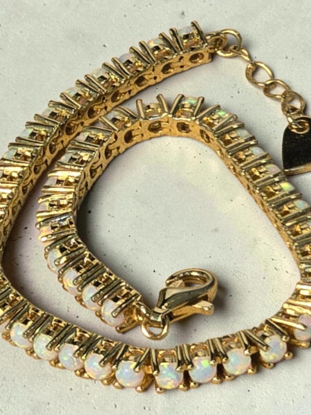 reveriebygemma fire opal tennis bracelet in 14kt gold plated sterling silver with a delicate heart charm detail.