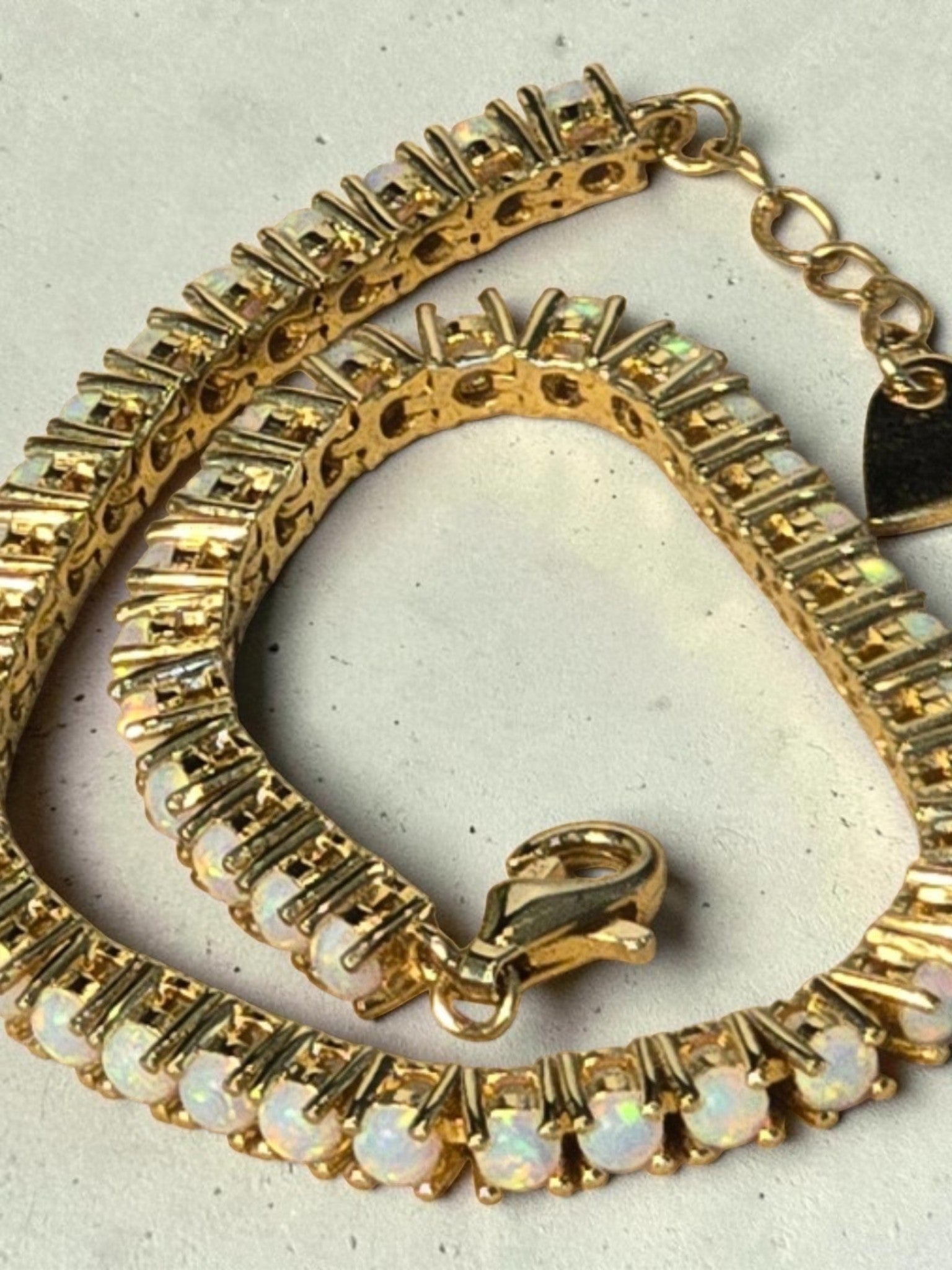 reveriebygemma fire opal tennis bracelet in 14kt gold plated sterling silver with a delicate heart charm detail.