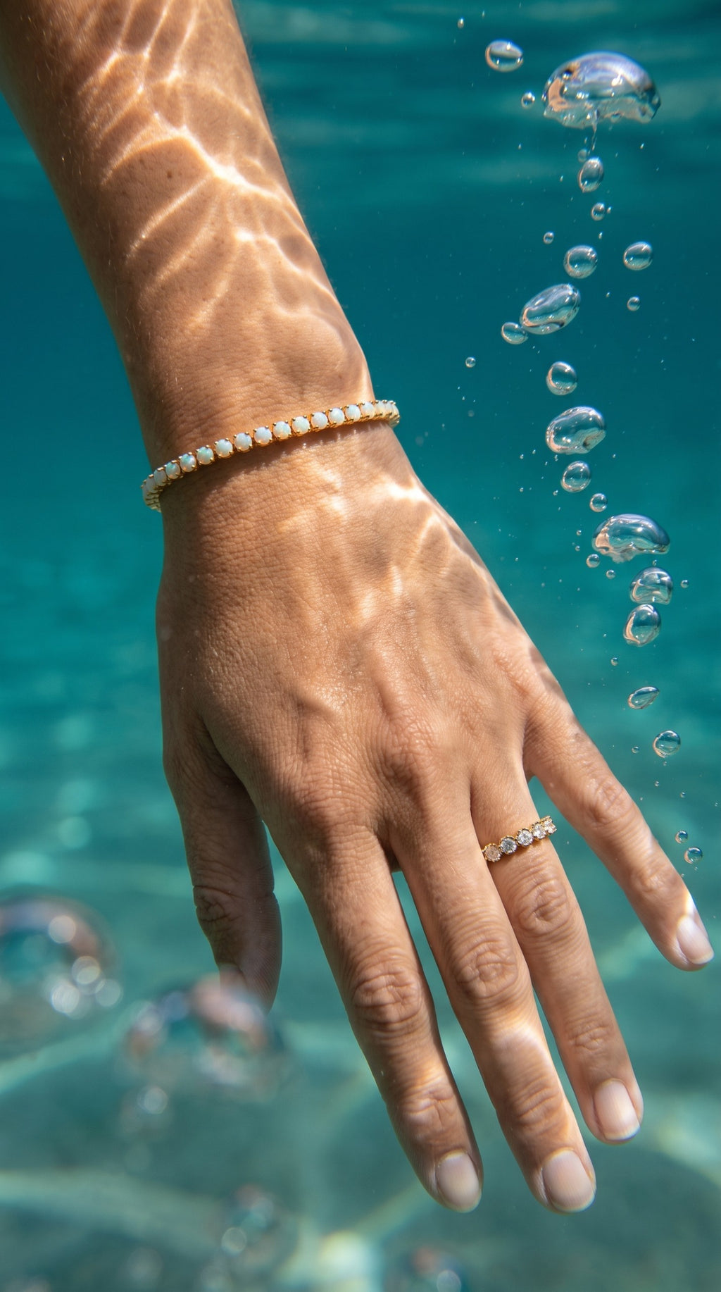 reveriebygemma fire opal tennis bracelet in 14kt gold plated silver worn underwater with bubbles and sunlight