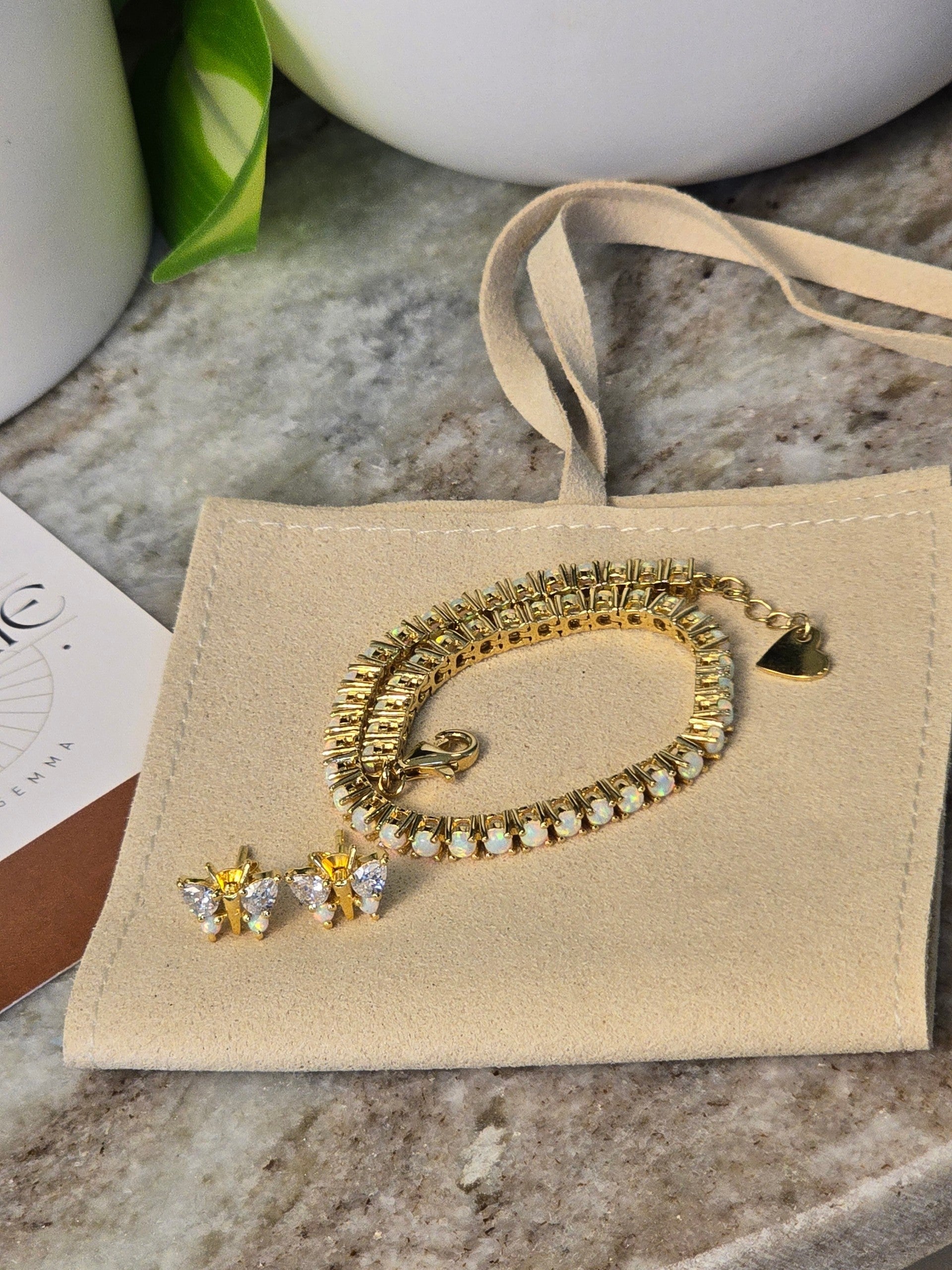 reveriebygemma fire opal tennis bracelet with heart charm and matching butterfly stud earrings on a velvet pouch