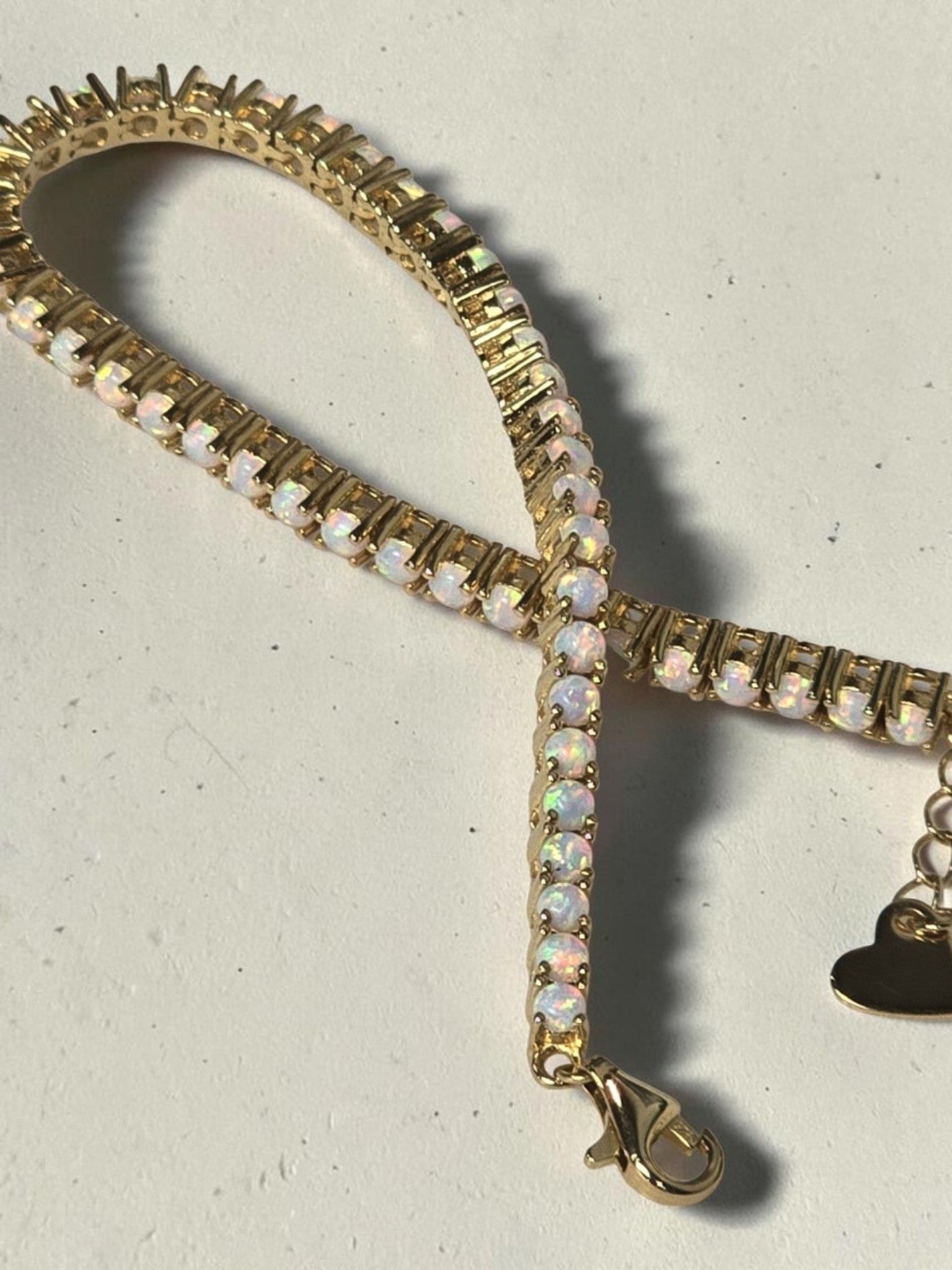 reveriebygemma fire opal tennis bracelet in 14kt gold plated sterling silver with a delicate heart charm accent.