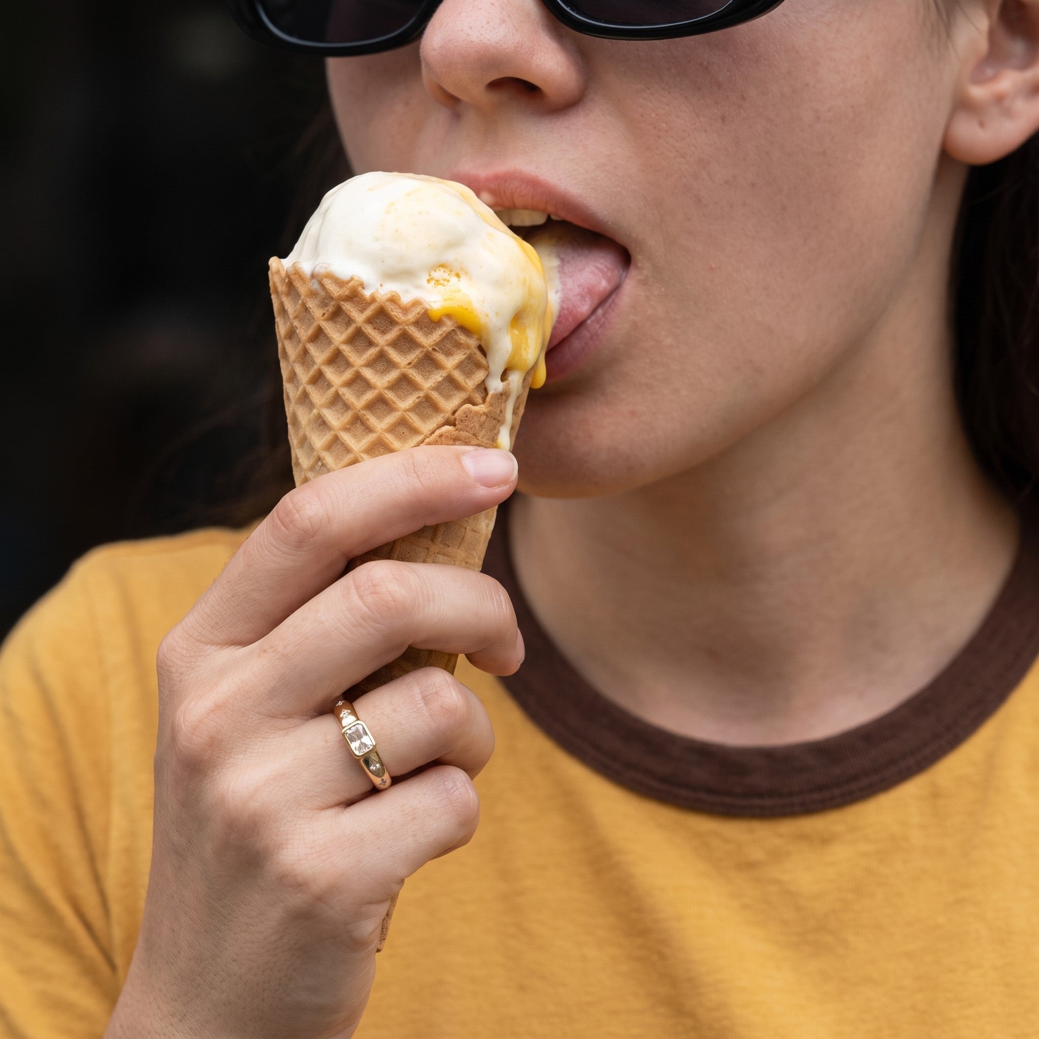 reveriebygemma gold plated sterling silver signet ring with baguette CZ stone worn on a finger holding an ice cream