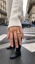 reveriebygemma 14kt gold plated baguette starburst signet ring worn on a finger with a cream sweater in a city street