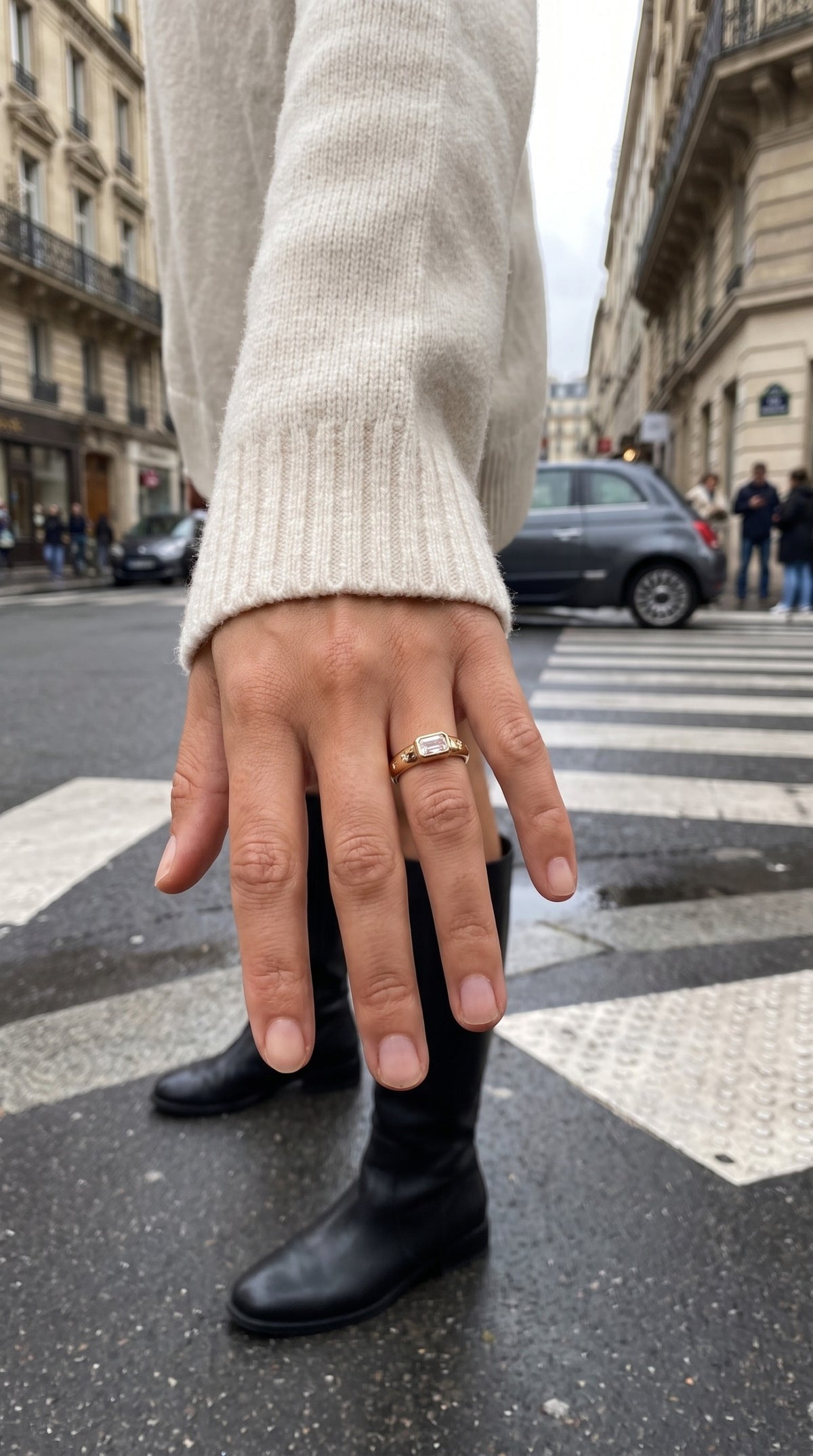 reveriebygemma 14kt gold plated baguette starburst signet ring worn on a finger with a cream sweater in a city street