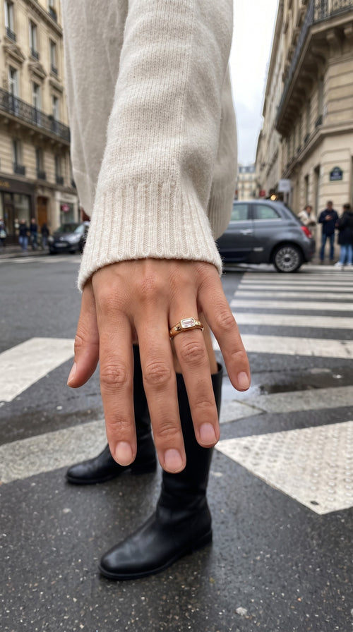 reveriebygemma 14kt gold plated baguette starburst signet ring worn on a finger with a cream sweater in a city street