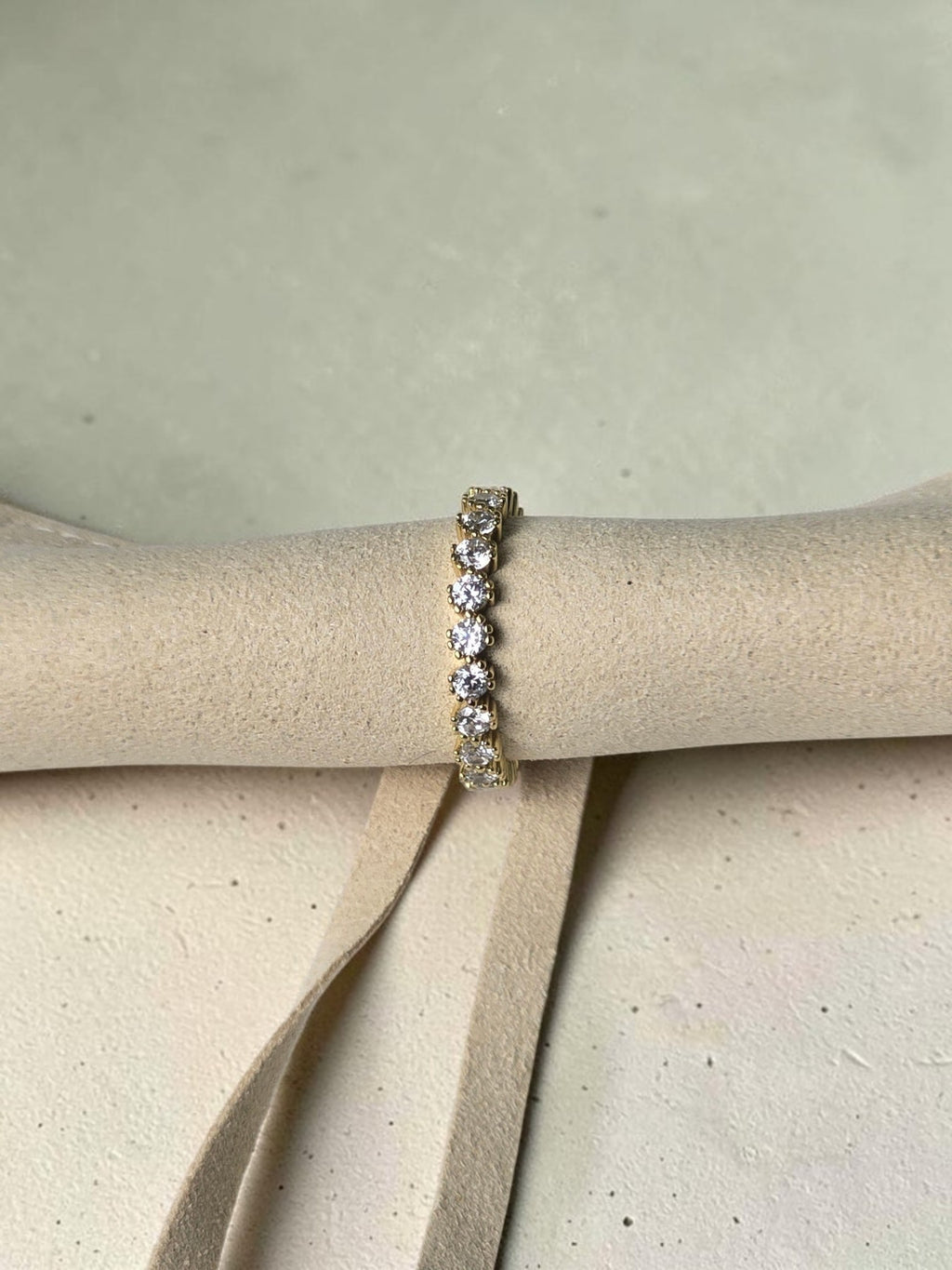 reveriebygemma 14kt gold plated sterling silver eternity band with bezel-set cubic zirconia stones on a display roll