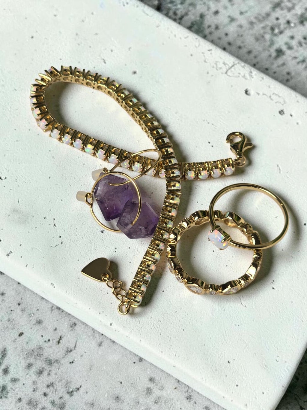 reveriebygemma gold bezel-set eternity band with cubic zirconia, displayed with a matching bracelet and amethyst ring.