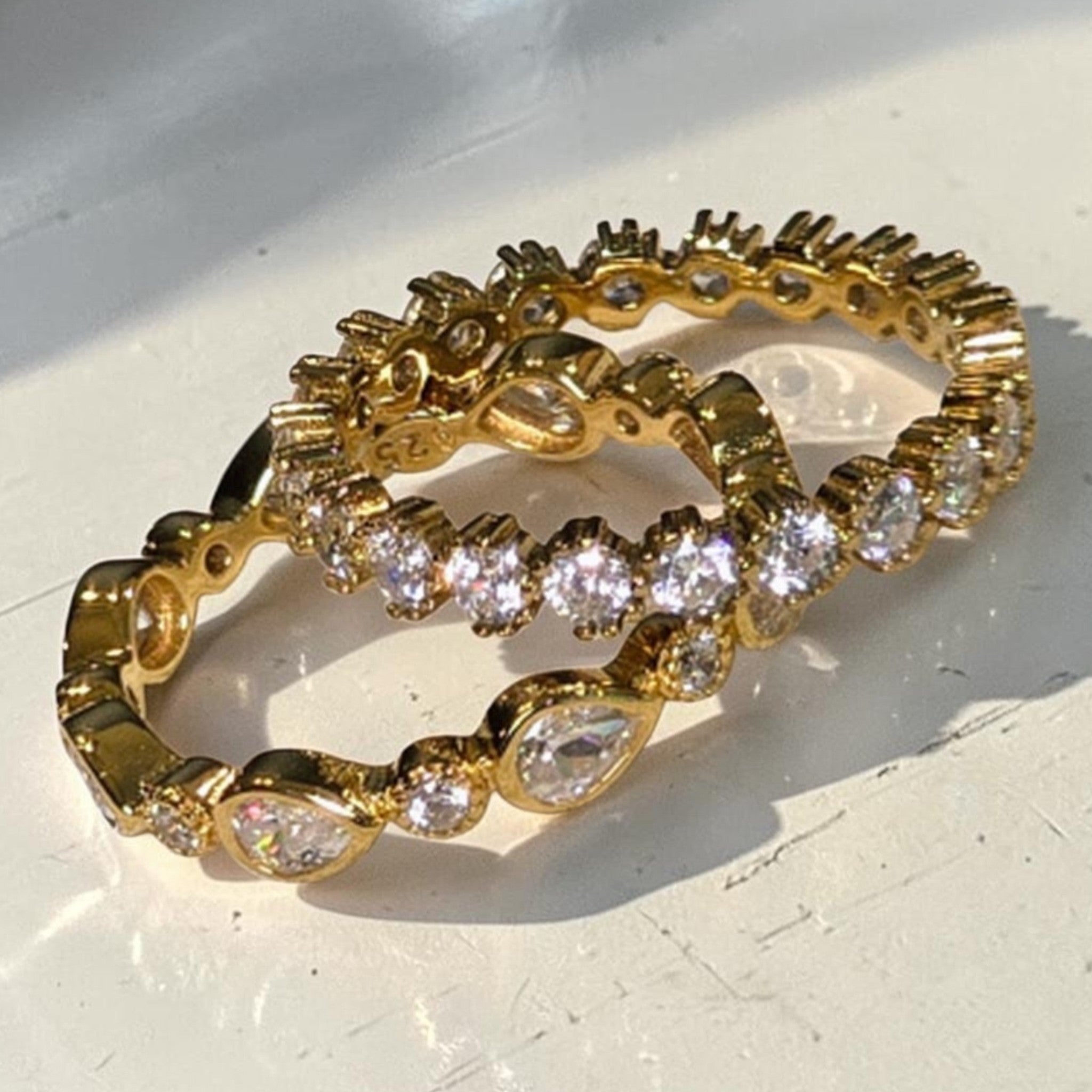 reveriebygemma gold plated sterling silver stacking rings with pear and round bezel-set cubic zirconia stones.