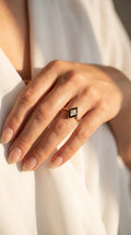reveriebygemma gold plated ring with a geometric black enamel signet face and a central cubic zirconia stone