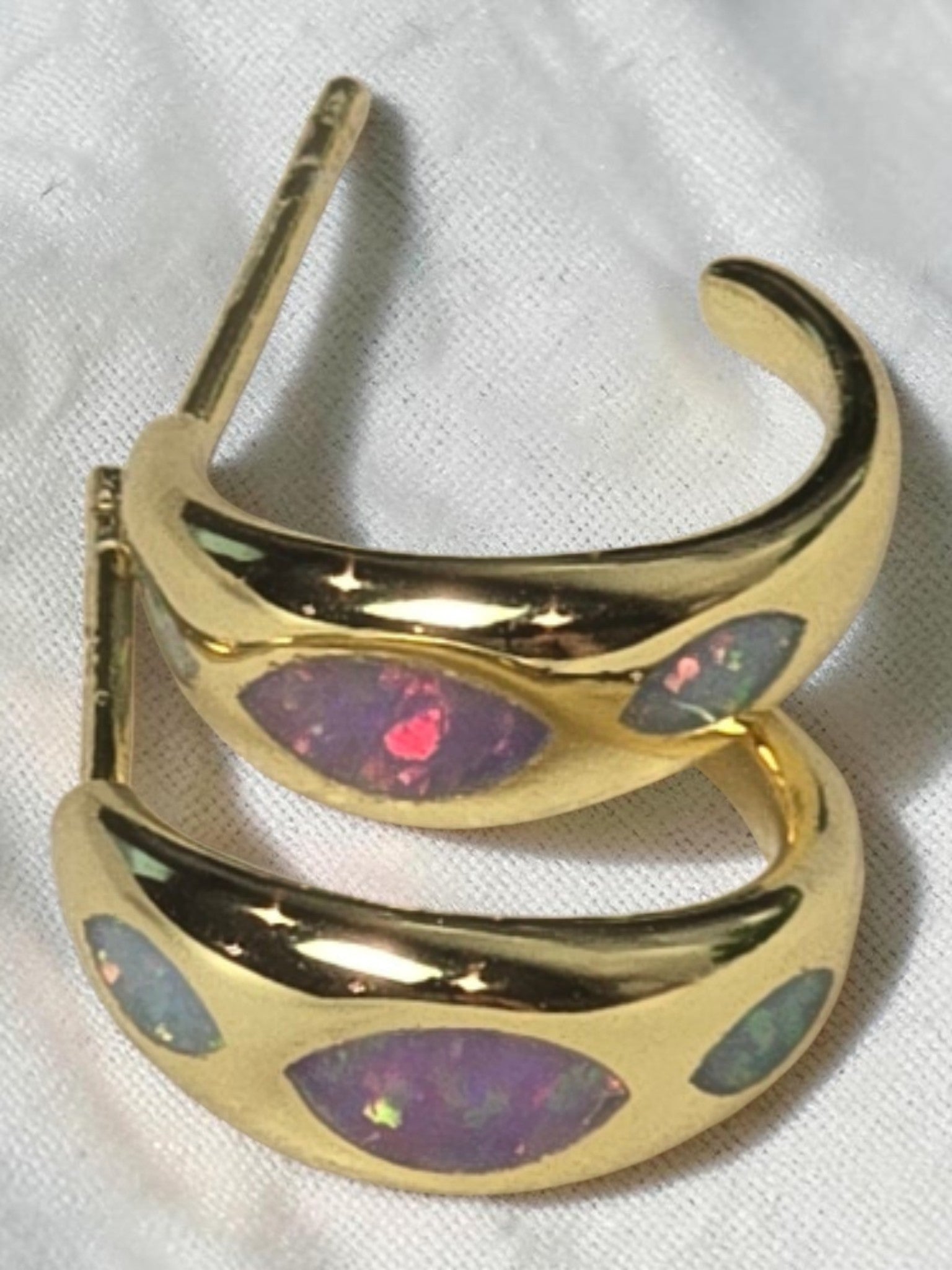 reveriebygemma 18kt gold vermeil huggie hoop earrings with marquise-shaped iridescent opal inlays on a white surface
