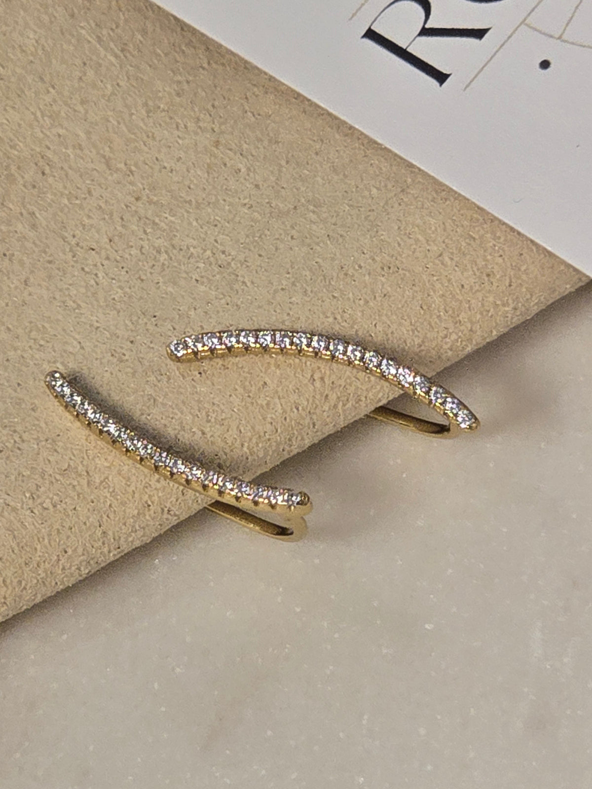 reveriebygemma Stargazer Dream gold pavé ear climbers with micro-cubic zirconia stones on a neutral display surface.