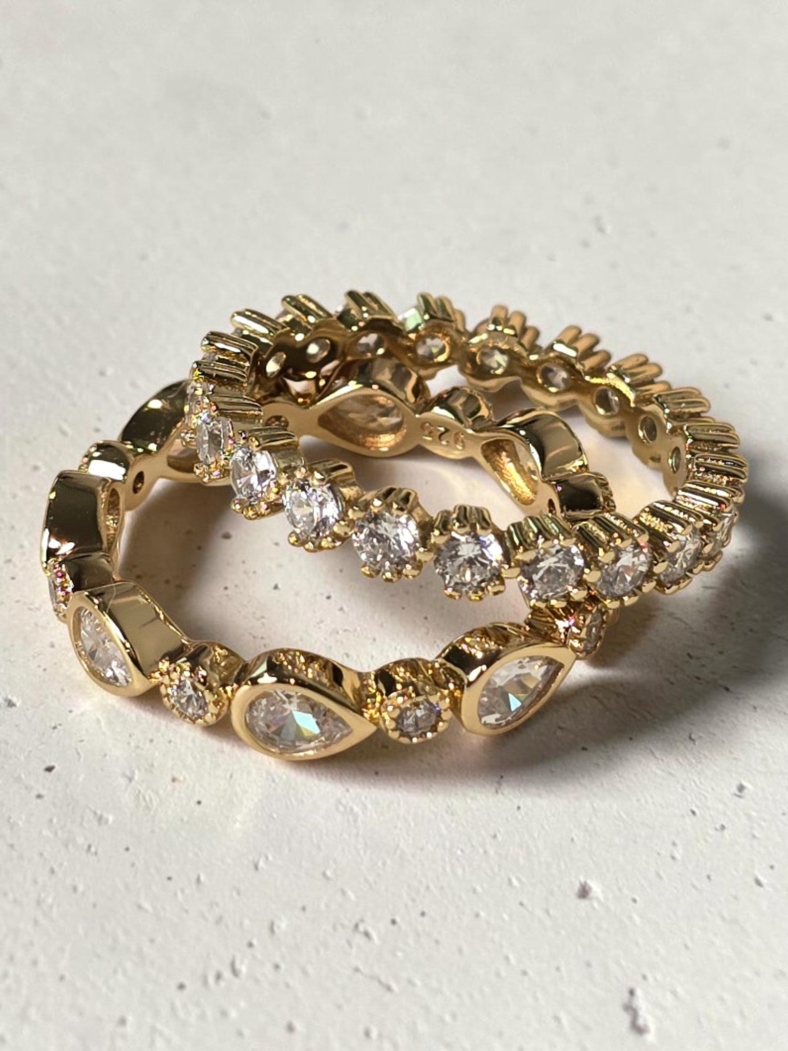 reveriebygemma gold plated sterling silver stacking rings with pear and round bezel-set cubic zirconia stones.