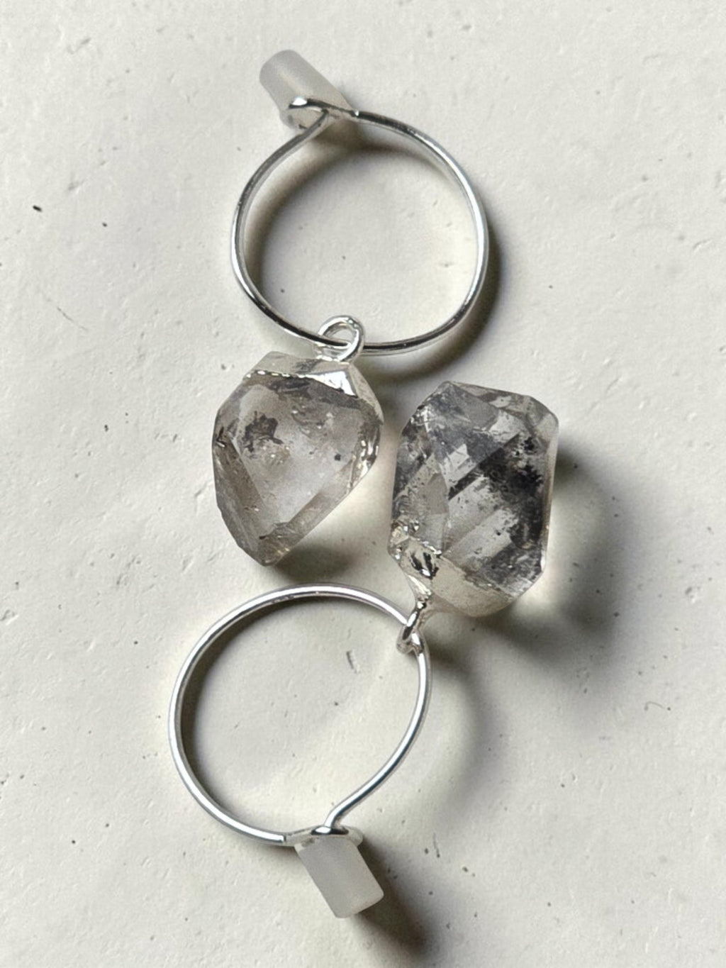 reveriebygemma sterling silver mini hoop earrings featuring raw-cut Herkimer diamond quartz crystals on a light surface