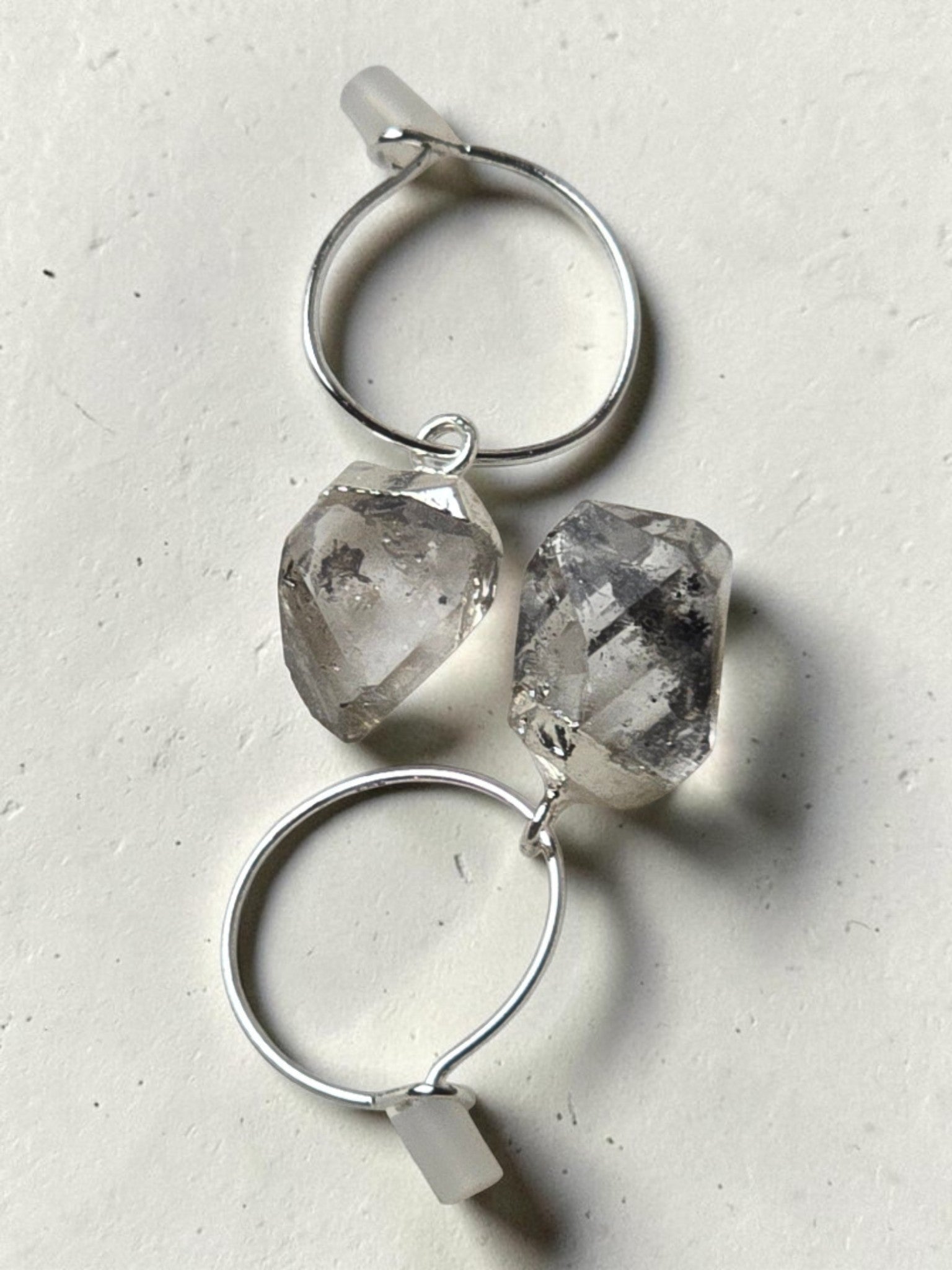 reveriebygemma sterling silver mini hoop earrings featuring raw-cut Herkimer diamond quartz crystals on a light surface