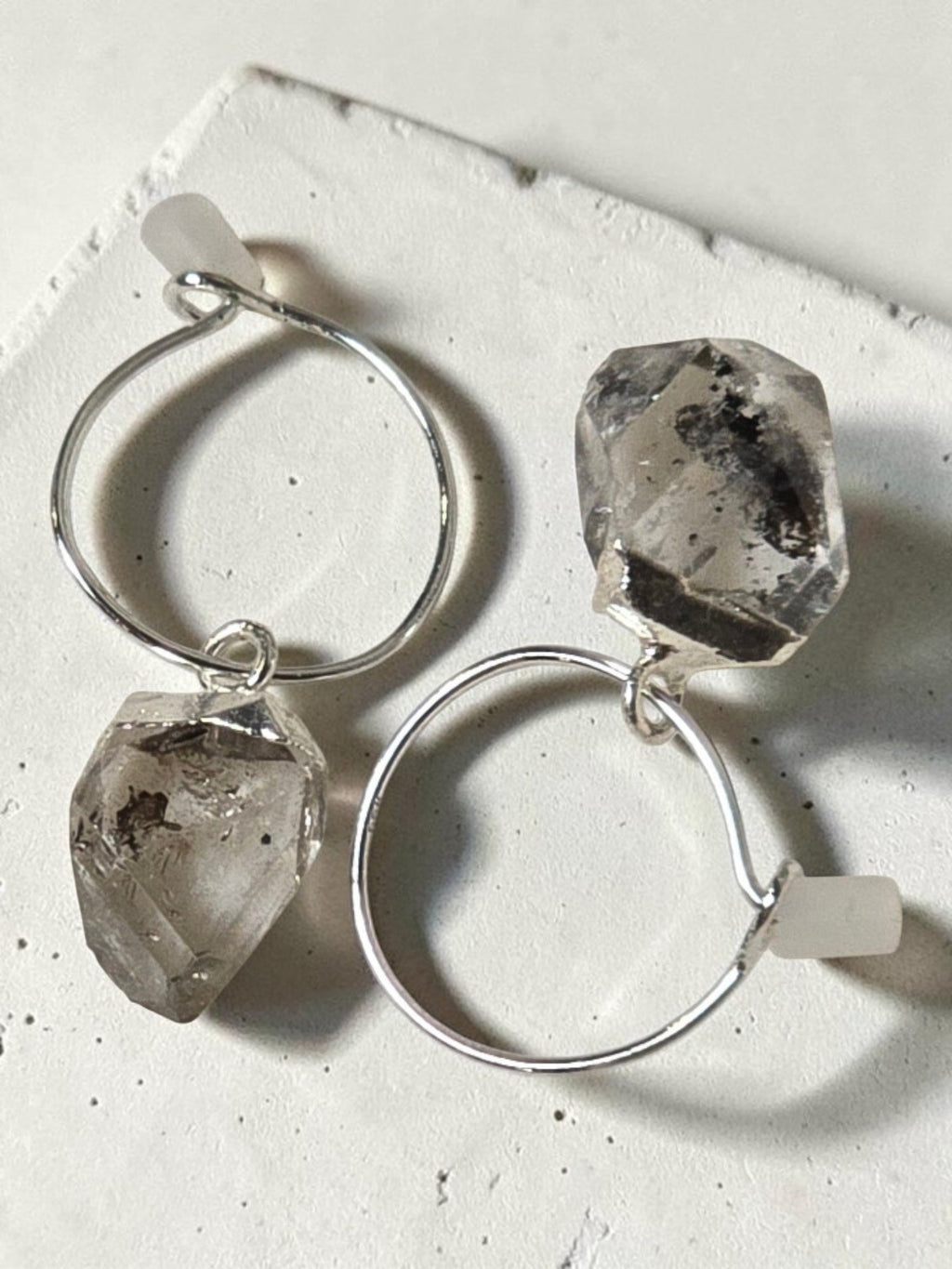 reveriebygemma sterling silver mini hoop earrings featuring raw-cut Herkimer diamond quartz crystals on a marble surface