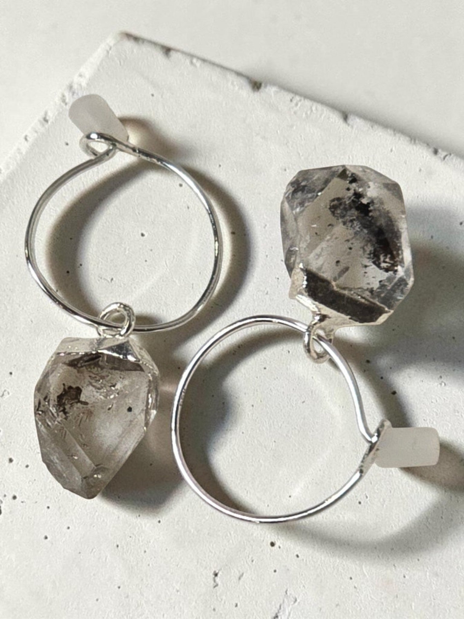 reveriebygemma sterling silver mini hoop earrings featuring raw-cut Herkimer diamond quartz crystals on a marble surface