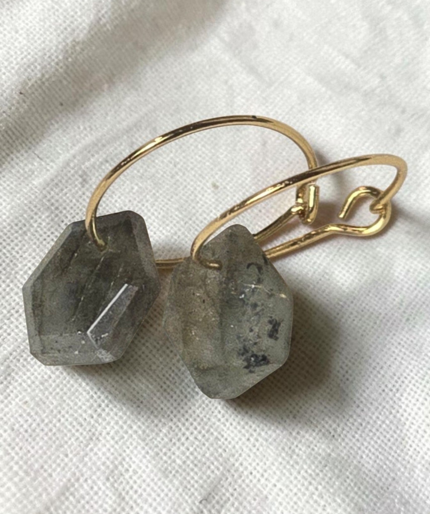 reveriebygemma gold plated huggie earrings featuring geometric labradorite stone drops on a white marble surface