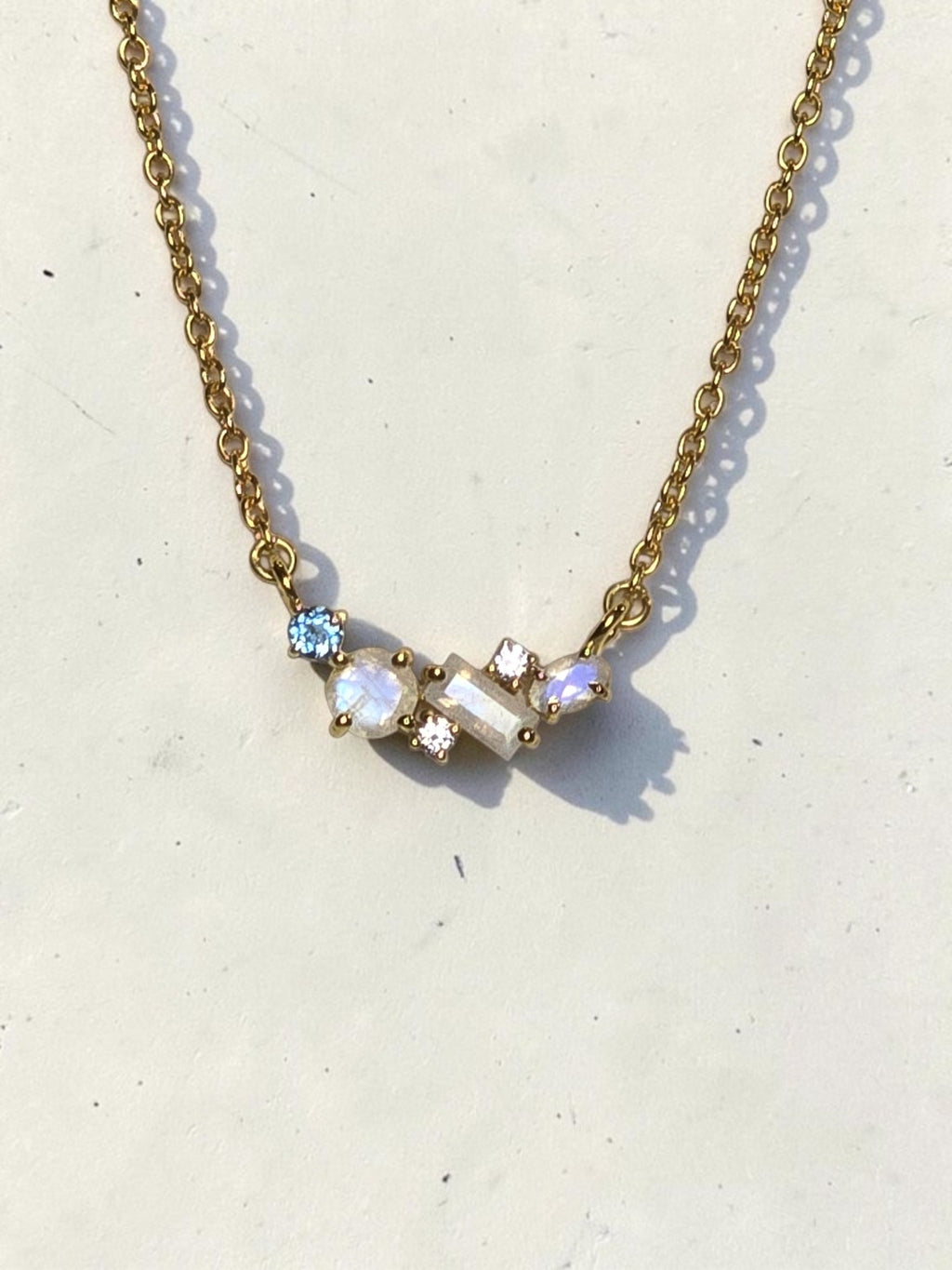 reveriebygemma 18kt gold vermeil necklace featuring an asymmetric cluster of rainbow moonstone, London blue, and white topaz.