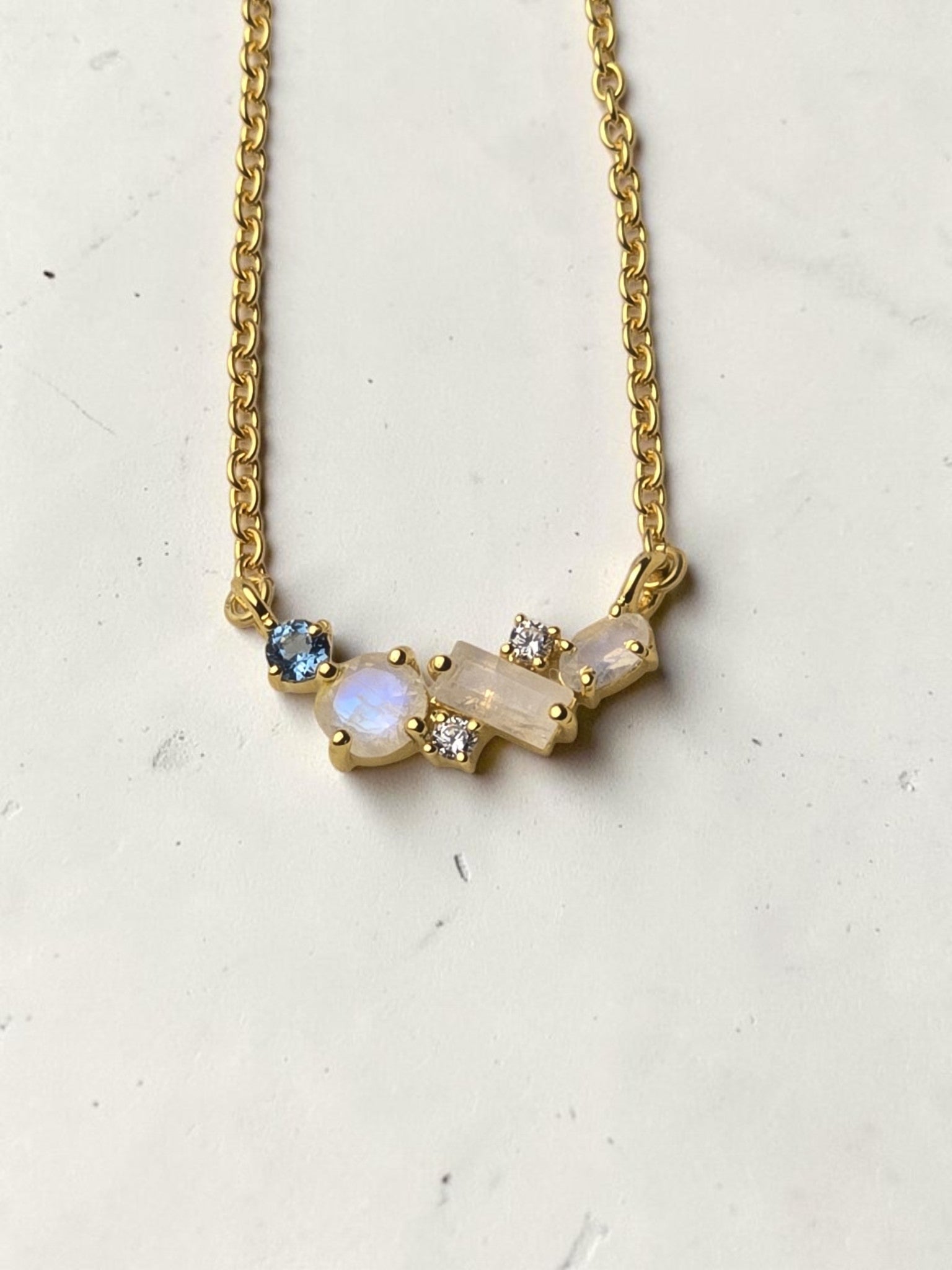 reveriebygemma celestial cluster necklace featuring rainbow moonstone, London blue topaz, and white topaz in gold vermeil