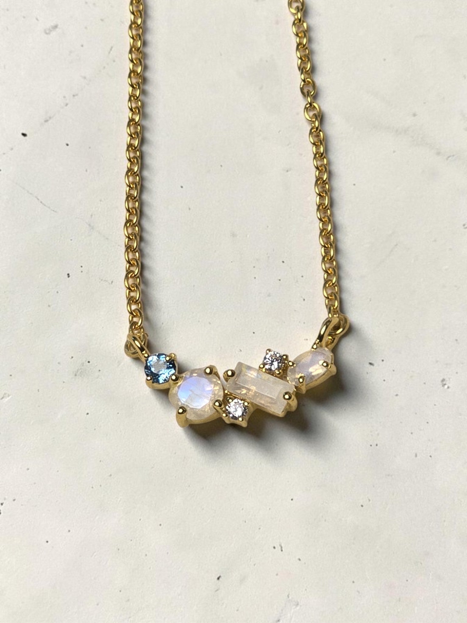 reveriebygemma celestial cluster necklace featuring rainbow moonstone, London blue topaz, and white topaz in gold vermeil