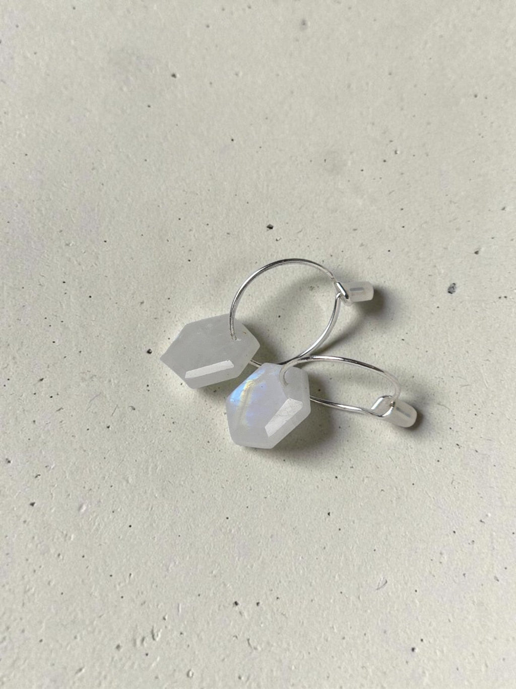 reveriebygemma raw moonstone drop huggie earrings in 925 sterling silver with geometric stones on a textured surface