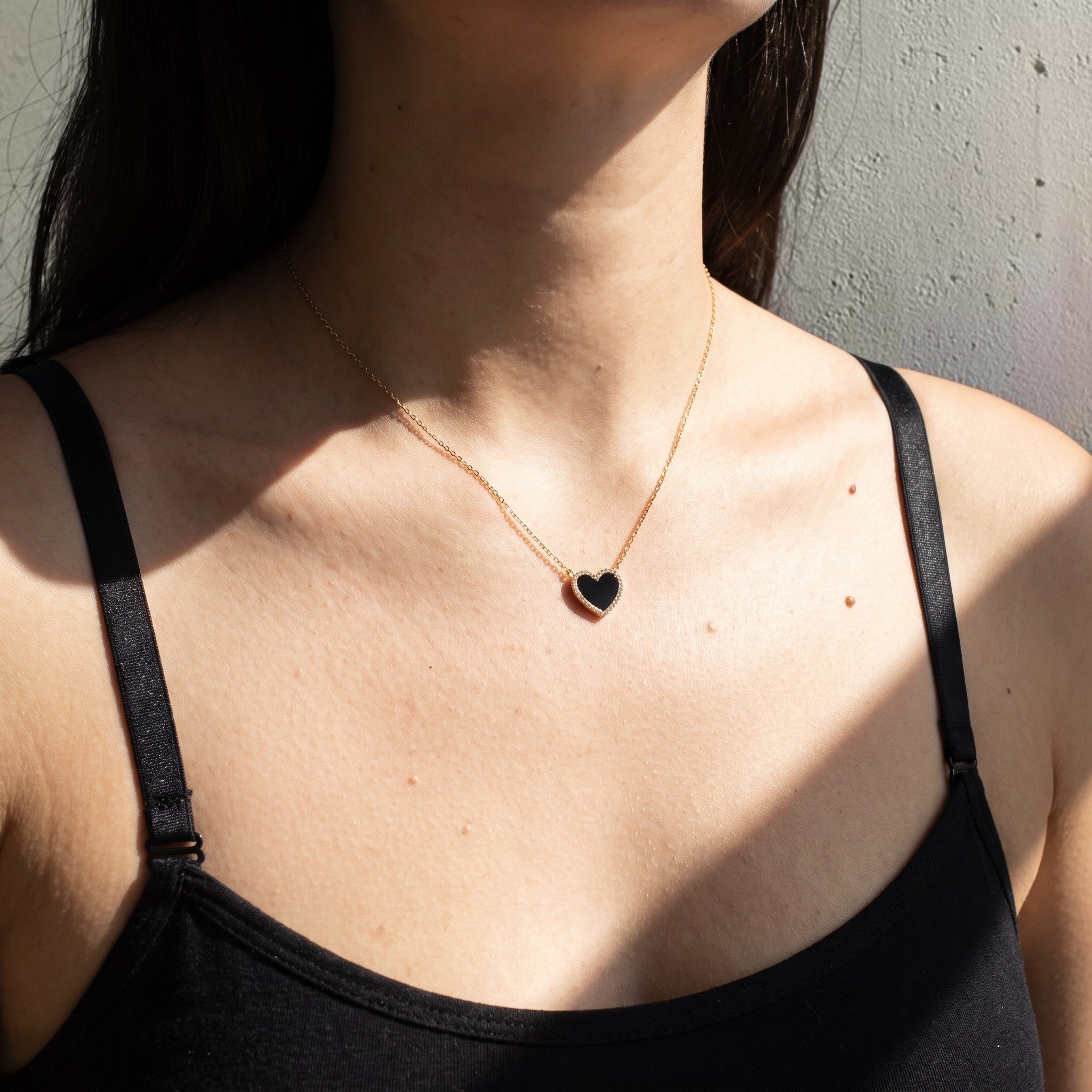 reveriebygemma Amoret heart pendant necklace featuring a black onyx stone with a CZ pave halo on a gold chain