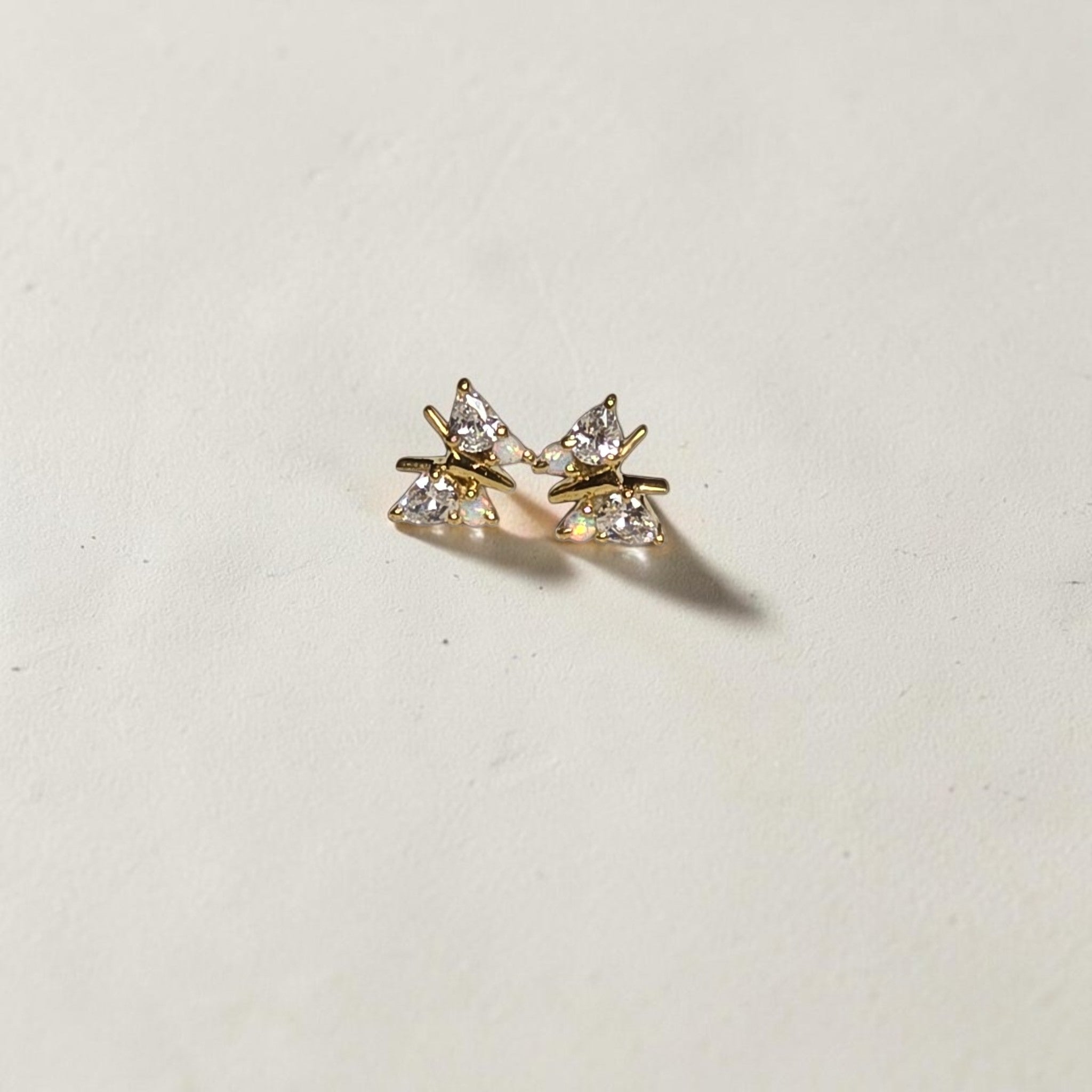 reveriebygemma butterfly stud earrings in 18kt gold vermeil with simulated opal and diamond accents on a textured base.